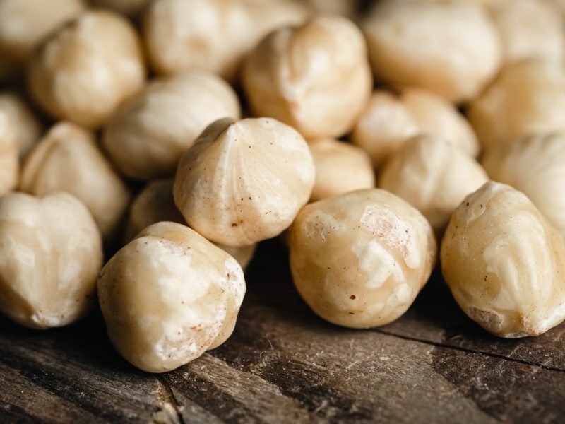 Heap of roasted hazelnuts close-up on a wooden background, macro shot.